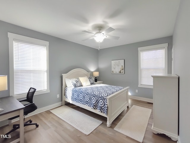 bedroom with multiple windows, wood finished floors, and baseboards