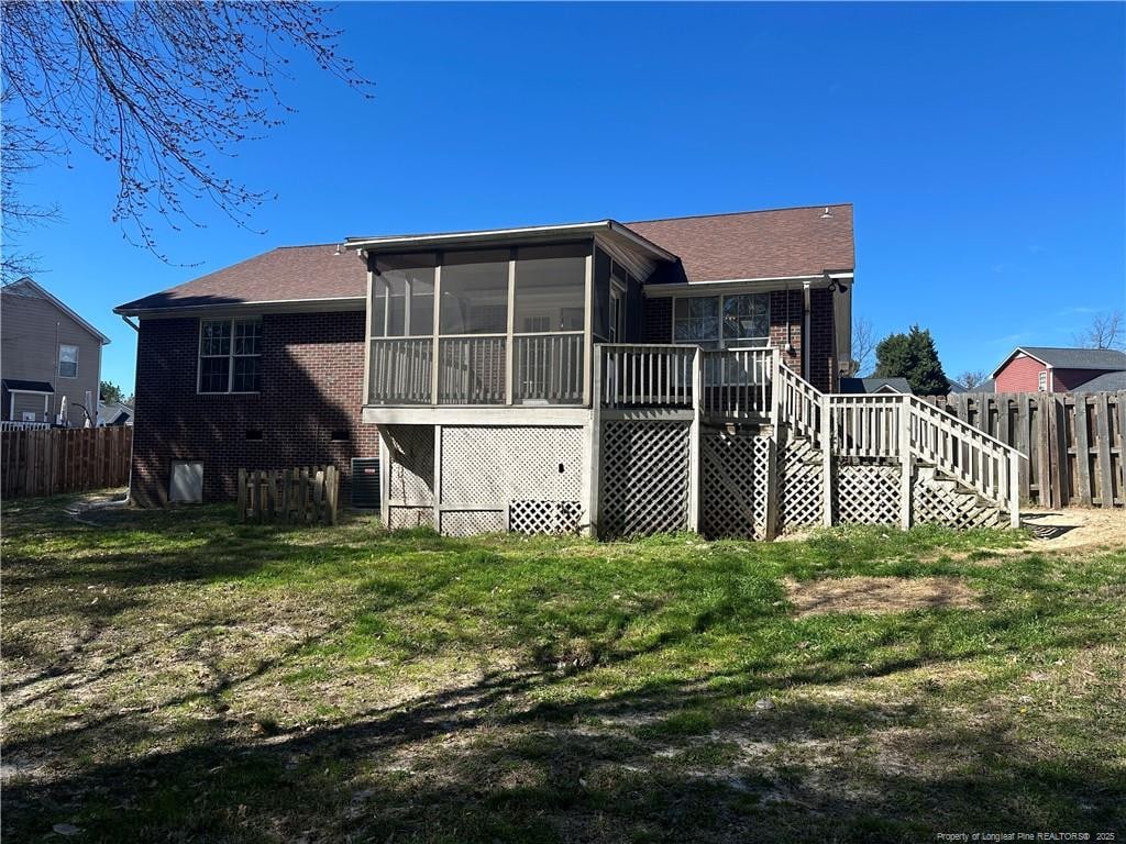 back of house with a sunroom, brick siding, fence, and stairs