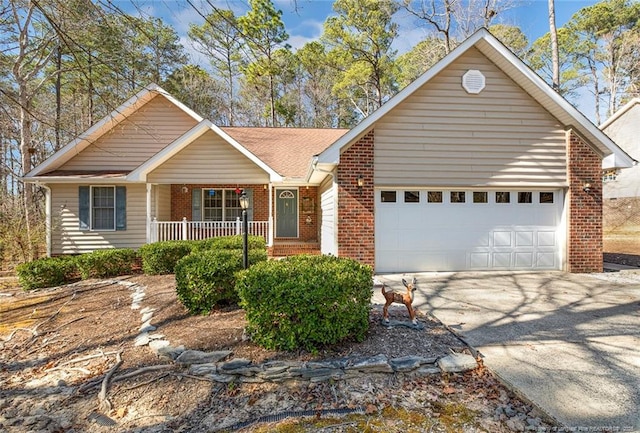 single story home with driveway, covered porch, a garage, and brick siding