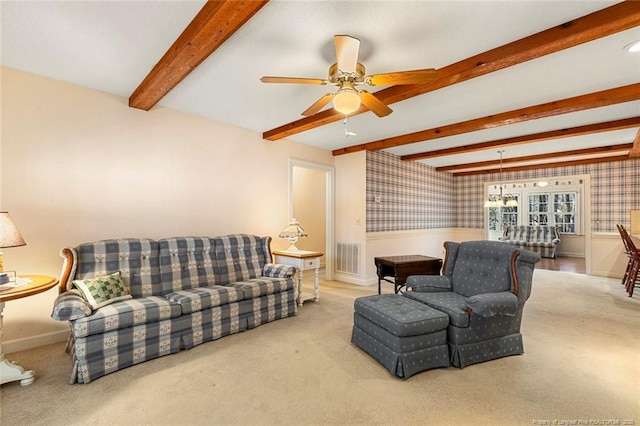 carpeted living area with visible vents, wallpapered walls, beamed ceiling, baseboards, and ceiling fan with notable chandelier