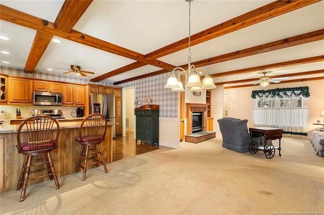 kitchen featuring light colored carpet, open floor plan, appliances with stainless steel finishes, beam ceiling, and wallpapered walls