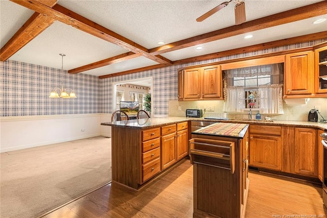 kitchen with a peninsula, wallpapered walls, a textured ceiling, and a wainscoted wall