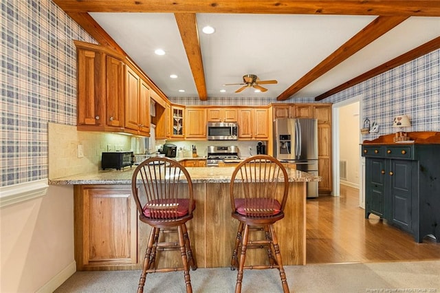 kitchen featuring recessed lighting, stainless steel appliances, a peninsula, beamed ceiling, and wallpapered walls