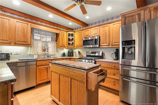 kitchen with stainless steel appliances, a center island, beamed ceiling, and light wood finished floors