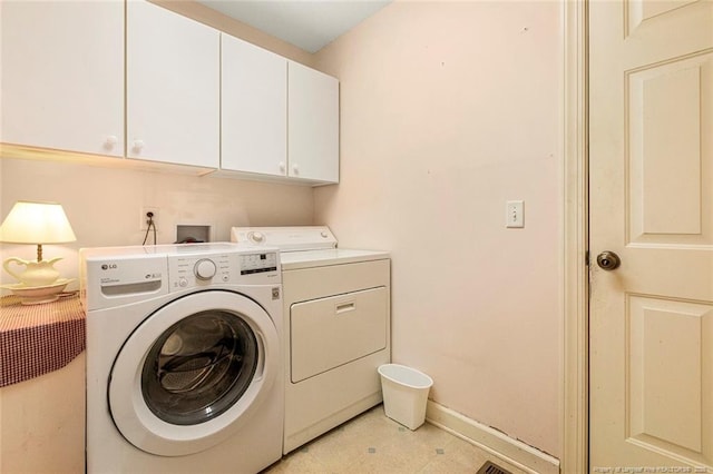 laundry area featuring washer and clothes dryer, cabinet space, and baseboards