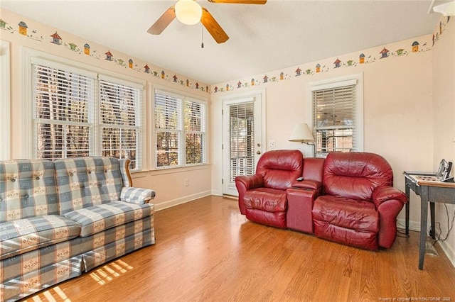 living room featuring ceiling fan, baseboards, and wood finished floors