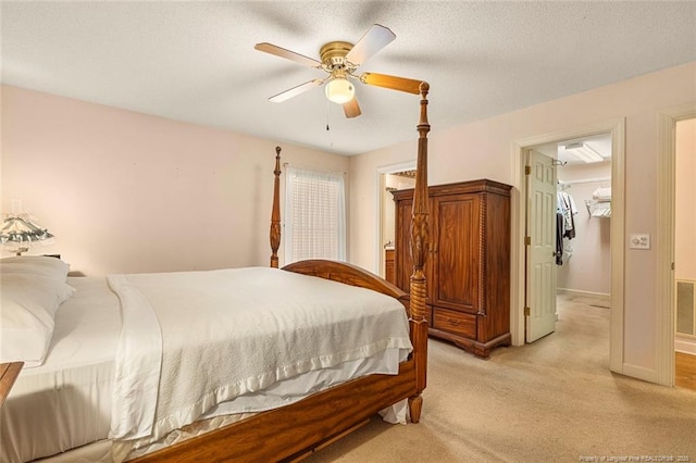 bedroom featuring ceiling fan, a textured ceiling, light carpet, visible vents, and baseboards