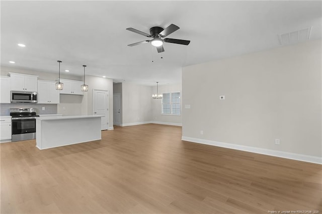 unfurnished living room with recessed lighting, ceiling fan with notable chandelier, visible vents, baseboards, and light wood-style floors