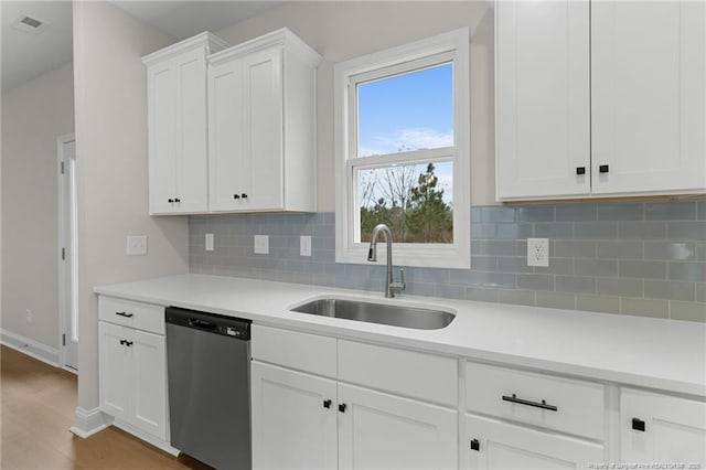 kitchen with light countertops, white cabinetry, a sink, wood finished floors, and dishwasher