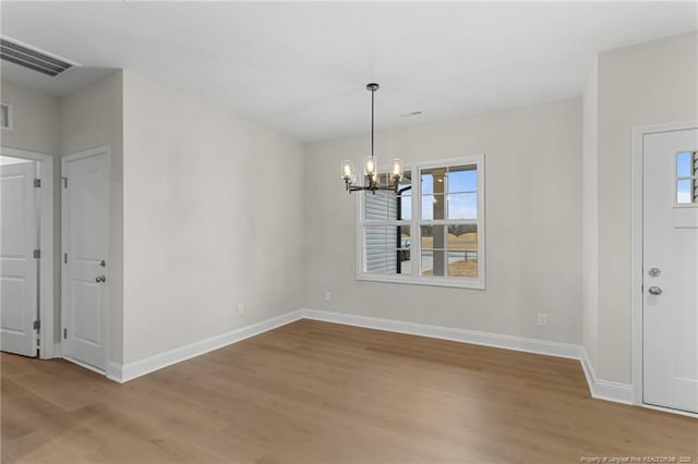 unfurnished dining area featuring plenty of natural light, wood finished floors, visible vents, and baseboards