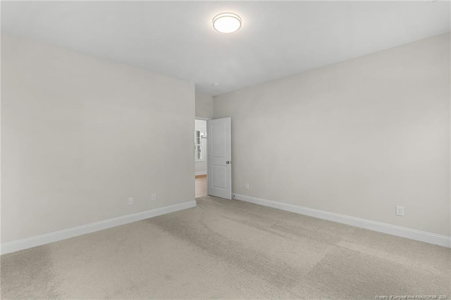 spare room featuring baseboards and light colored carpet