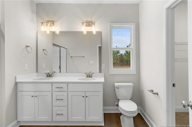 bathroom featuring baseboards, a sink, toilet, and double vanity