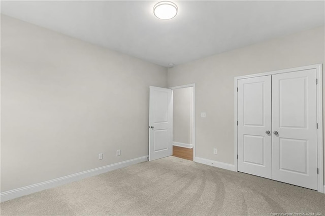 unfurnished bedroom with carpet, baseboards, and a closet