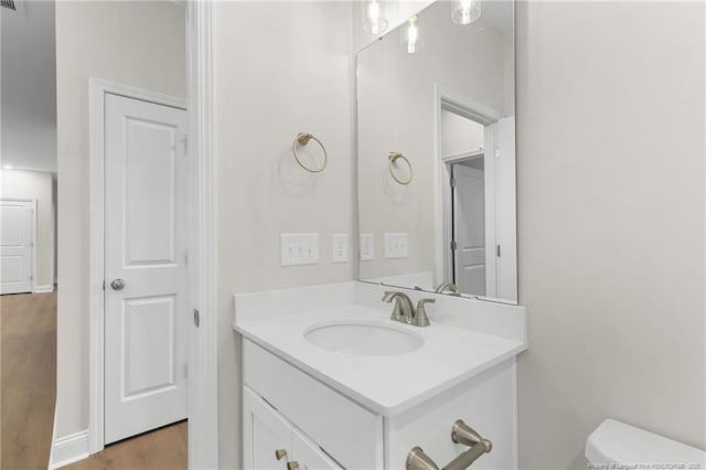 bathroom with wood finished floors, vanity, and toilet