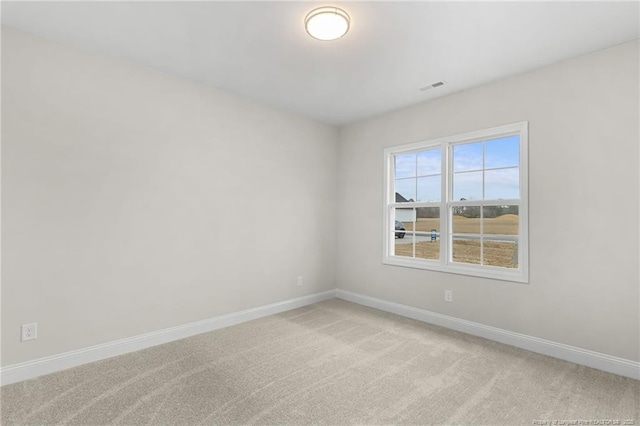 spare room with light colored carpet, visible vents, and baseboards