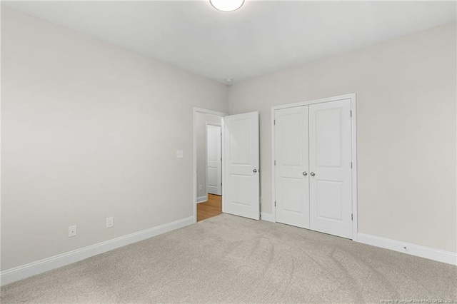 unfurnished bedroom with a closet, carpet, and baseboards