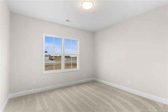 carpeted spare room with visible vents and baseboards