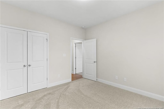 unfurnished bedroom with a closet, carpet, and baseboards