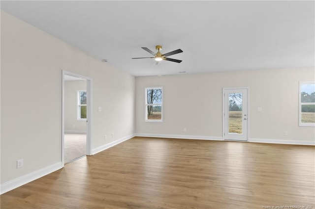 empty room with a wealth of natural light, ceiling fan, baseboards, and wood finished floors