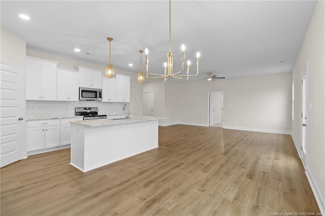 kitchen with stainless steel appliances, decorative backsplash, a sink, and white cabinets