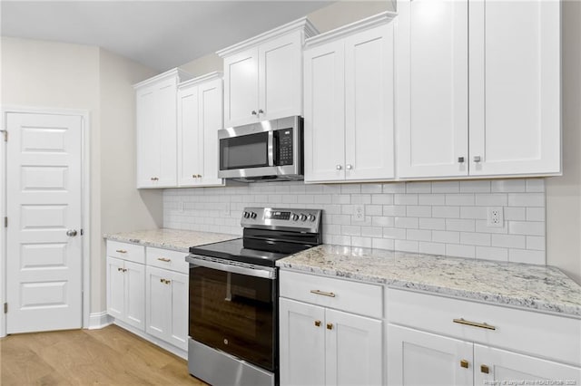 kitchen featuring light stone countertops, light wood-style flooring, white cabinetry, and stainless steel appliances