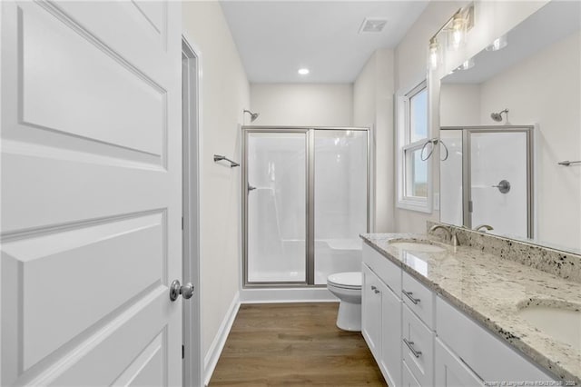 full bath with a sink, wood finished floors, a shower stall, and visible vents