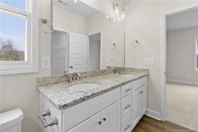 full bathroom with double vanity, baseboards, toilet, and a sink