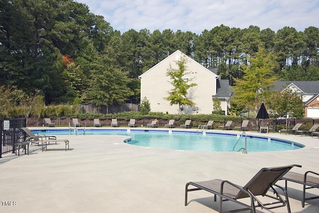 community pool with a patio area and fence