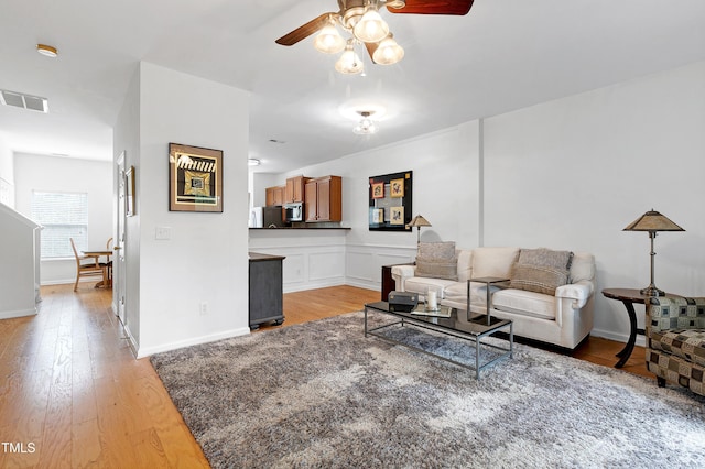 living area featuring visible vents, ceiling fan, light wood-style flooring, and baseboards