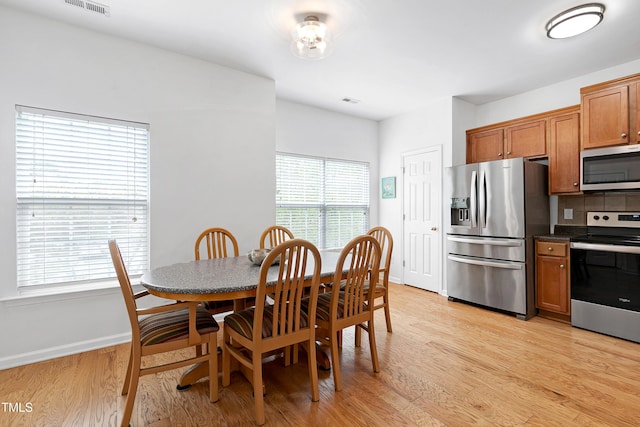 dining space featuring light wood-style flooring, visible vents, and baseboards