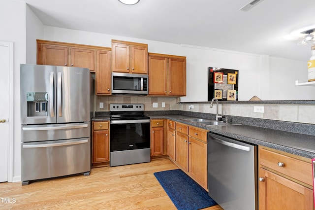 kitchen with appliances with stainless steel finishes, a sink, visible vents, and tasteful backsplash