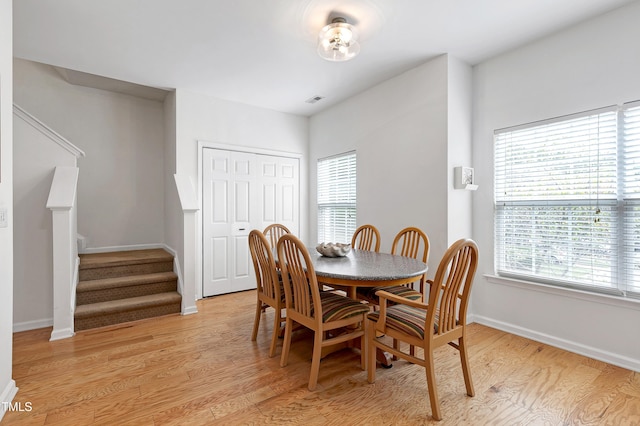 dining area with light wood finished floors, stairway, visible vents, and baseboards