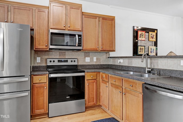 kitchen with stainless steel appliances, backsplash, dark countertops, and a sink