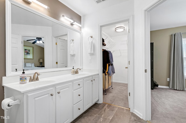 bathroom with double vanity, visible vents, a walk in closet, and a sink