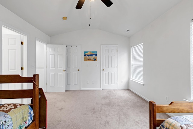 bedroom featuring lofted ceiling, carpet floors, a ceiling fan, baseboards, and two closets