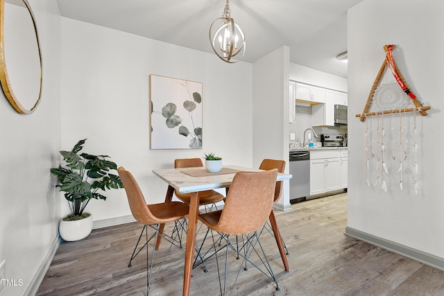 dining area featuring baseboards, a chandelier, and light wood finished floors