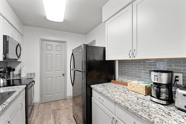 kitchen with light wood finished floors, backsplash, light stone countertops, stainless steel appliances, and white cabinetry