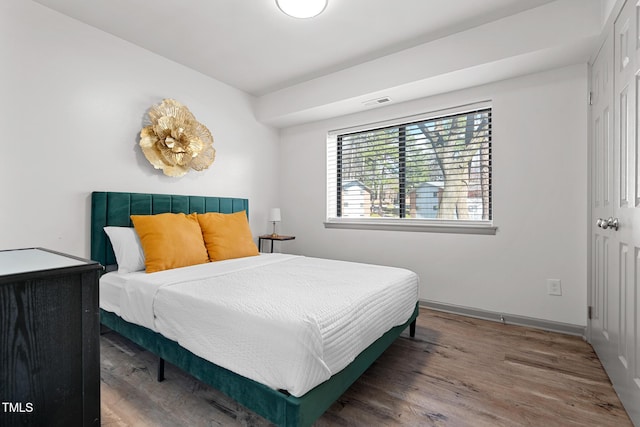 bedroom with wood finished floors, visible vents, and baseboards