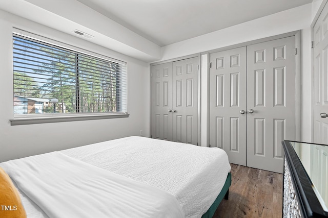 bedroom featuring visible vents, multiple closets, and dark wood-style flooring