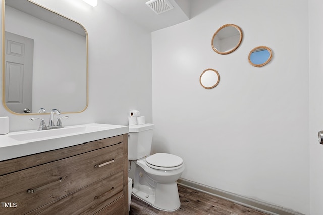 bathroom with visible vents, toilet, vanity, and wood finished floors