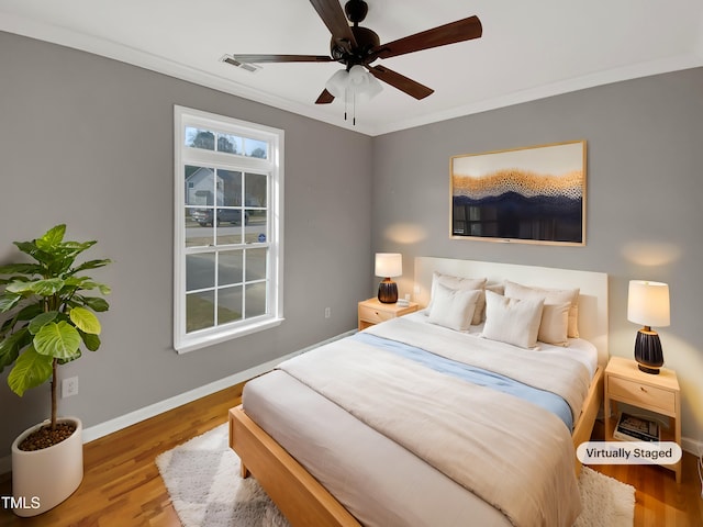 bedroom featuring visible vents, baseboards, ceiling fan, wood finished floors, and crown molding