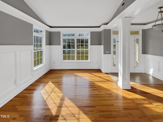 interior space with lofted ceiling, decorative columns, visible vents, and wainscoting