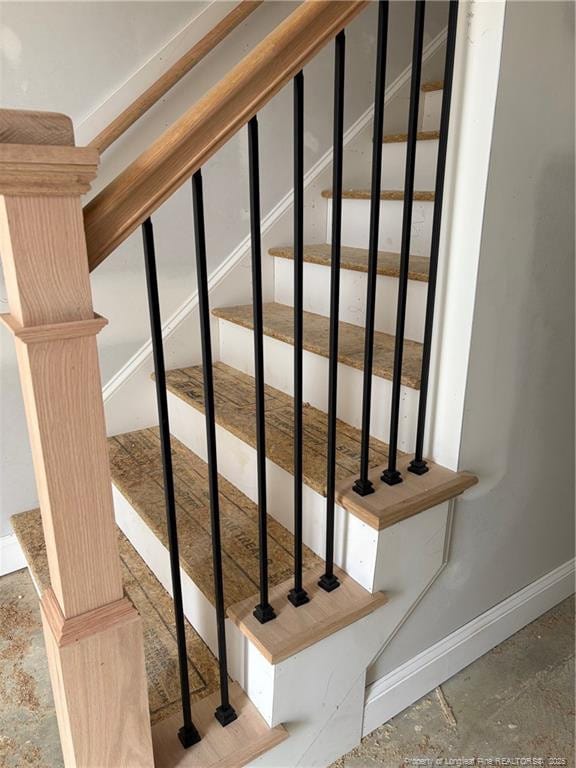 stairs featuring baseboards and unfinished concrete flooring