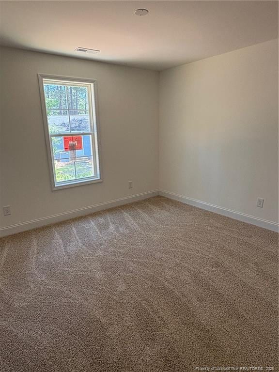 spare room featuring light carpet and baseboards