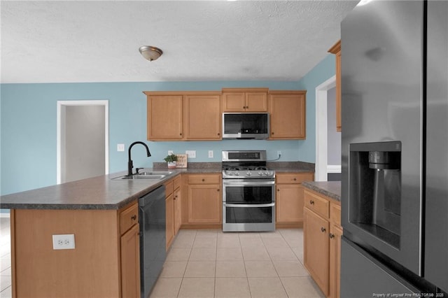 kitchen featuring dark countertops, a peninsula, stainless steel appliances, and a sink