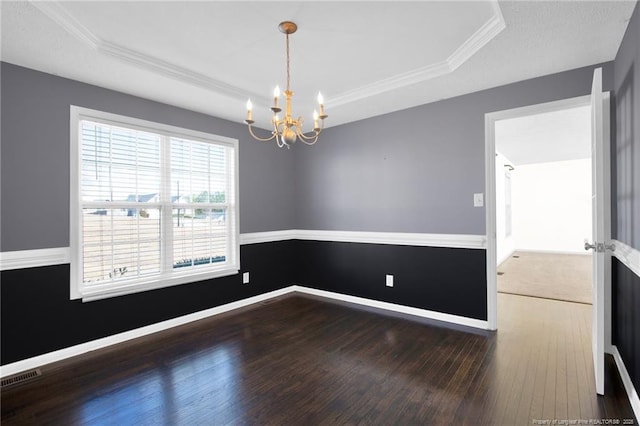 spare room featuring a tray ceiling, wood-type flooring, visible vents, and baseboards