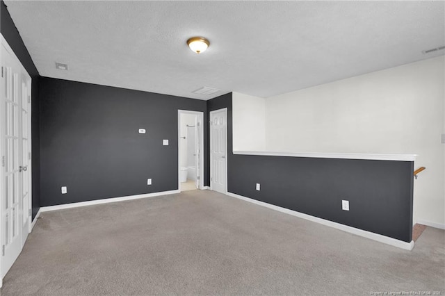 unfurnished room featuring carpet floors, baseboards, visible vents, and a textured ceiling