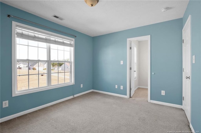 carpeted spare room with visible vents and baseboards