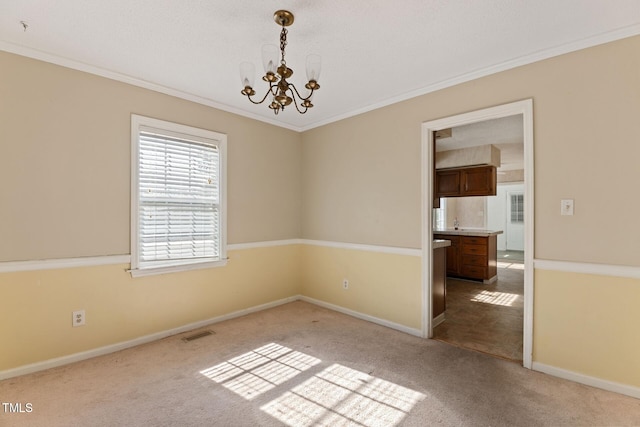 carpeted spare room with visible vents, crown molding, and an inviting chandelier