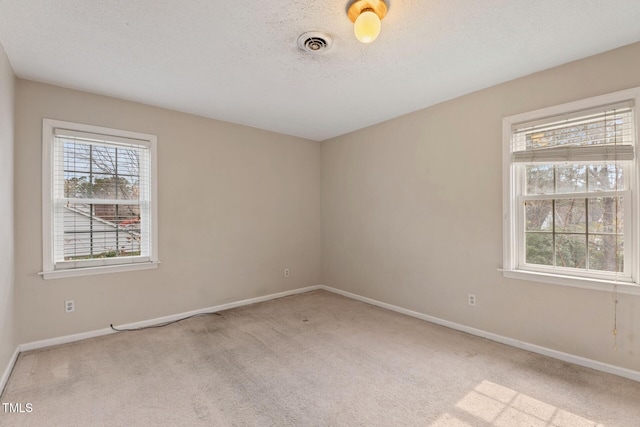 unfurnished room featuring a textured ceiling, carpet flooring, visible vents, and baseboards